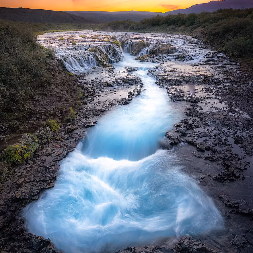 Blue water flowing through a rocky Icelandic landscape at sunset